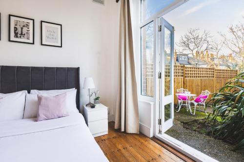 a bedroom with a bed and a sliding glass door at Beautiful one bed garden flat in Muswell hill in London