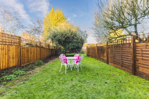 two chairs and a table in a backyard with a fence at Beautiful one bed garden flat in Muswell hill in London