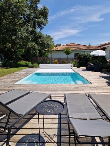 a swimming pool with two tables and chairs next to it at Villa Nelson Classée 3 étoiles in Moliets-et-Maa