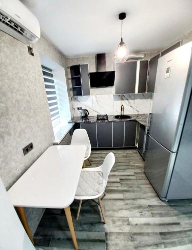 a kitchen with a table and two chairs and a refrigerator at Апартаменти Дендропарк in Kropyvnytskyi