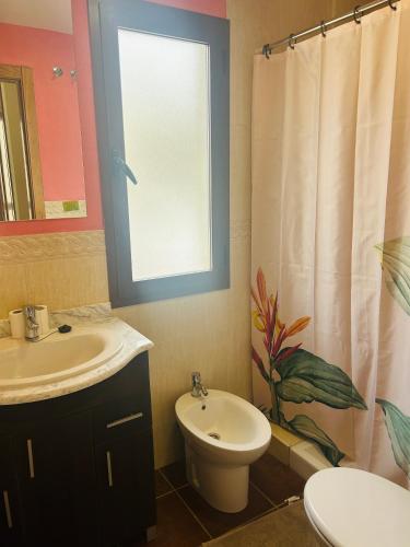 a bathroom with a sink and a toilet and a window at La Escapada in El Ronquillo