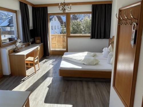 a bedroom with a bed and a desk and a sink at Hotel Alpina nature-wellness in Wenns