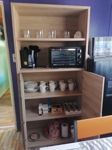 a shelf with cups and a microwave and a refrigerator at Apartamento Cuadruple in Isla de Maipo