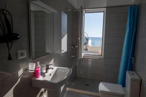 a bathroom with a sink and a mirror and a window at Roxhensi Apartments in Shëngjin