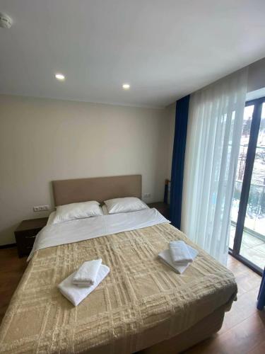 a bedroom with a large bed with two towels on it at Frostwood Residence Orbi in Bakuriani