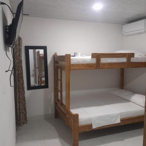 a room with two bunk beds and a mirror at Villa del coco Hospedajes in Arboletes