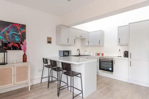 a kitchen with white cabinets and bar stools at Stylish 2 Bedroom Apartment in Liverpool - Gateacre Village - Free Parking in Liverpool