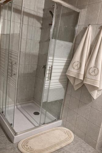 a shower with a glass door and towels in a bathroom at GANCZ APARTMAN in Sárvár