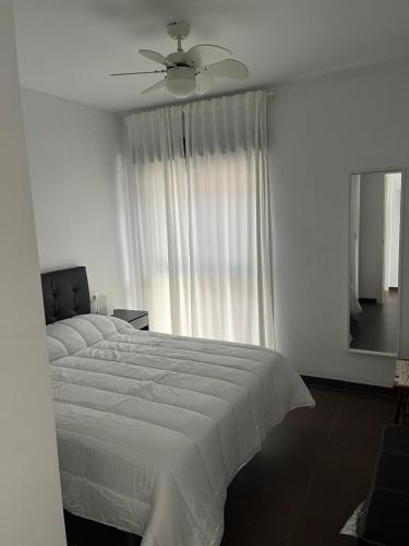 a bedroom with a white bed and a ceiling fan at over the sea in El Morche