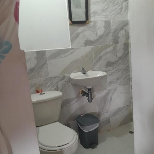 a bathroom with a white toilet and a sink at Villa del coco Hospedajes in Arboletes