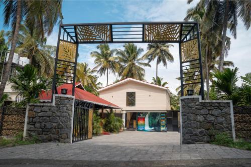 a gate in front of a building with palm trees at Mountain river farm resort in Agali