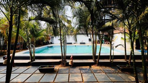 a swimming pool with palm trees in front of a building at Patnem Garden Resort in Patnem
