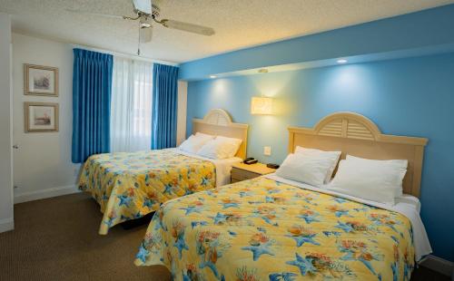 a hotel room with two beds and blue walls at Concord Suites in Avalon