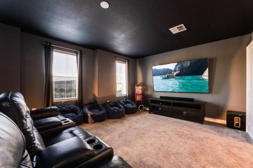 a living room with a couch and a flat screen tv at Amazing 8br w pool theater game room by Disney in Kissimmee