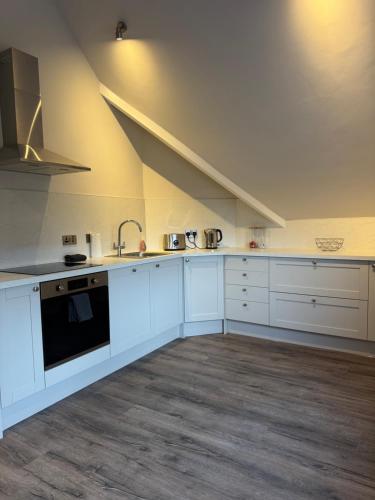 a kitchen with white cabinets and a black oven at MacGregor Ranch Apartment in Spean Bridge
