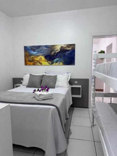 a white bedroom with a bed with flowers on it at Hotel Tropical in Torres