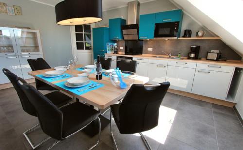 a kitchen with a wooden table and black chairs at Villa Aquila Luxus-Maisonette Ferienträume Dachterrasse in Göhren-Lebbin