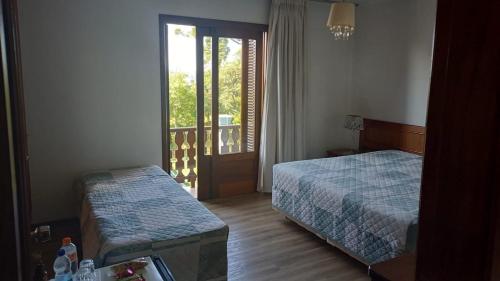 a hotel room with two beds and a window at Hotel San Carlos in Carlos Barbosa