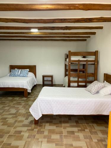 a bedroom with two beds and a wooden ceiling at Hotel Arcoiris Mesa de los Santos in Los Santos