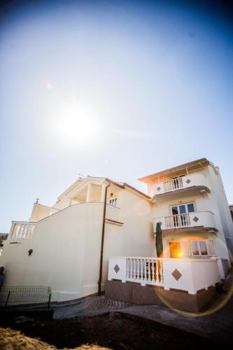 a large white house with a balcony on the side of it at Apartments Skapul in Lopar