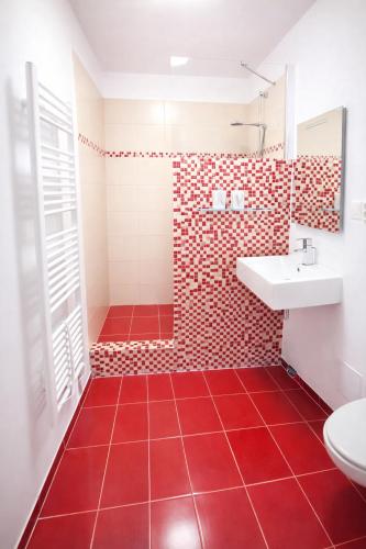 a red tiled bathroom with a sink and a toilet at The Meetinka - Peaceful Stay, Jeseníky in Jeseník