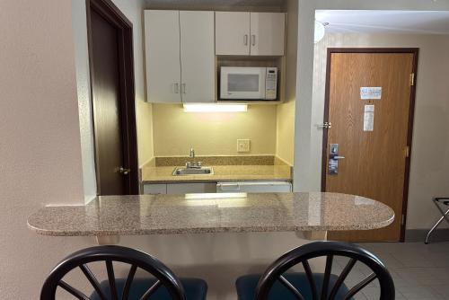 a kitchen with a counter and a sink and some chairs at Super 8 by Wyndham Mars/Cranberry/Pittsburgh Area in Cranberry Township