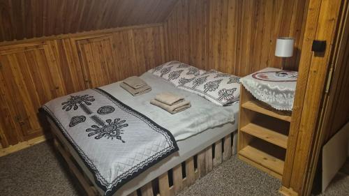 a small bed in a room with a wooden wall at Limba in Ząb