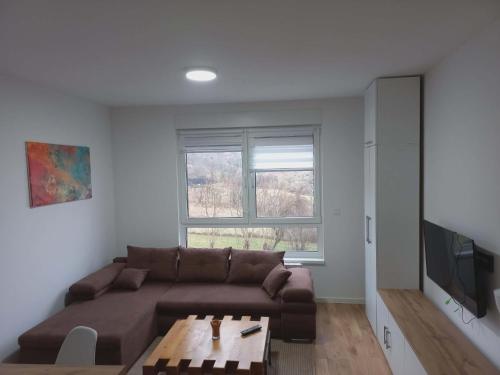 a living room with a brown couch and a table at Apartman Symbol in Tuzla