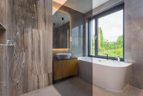 a bathroom with a bath tub and a sink at Villa Titanium in Opatija