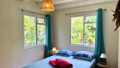 a bedroom with two windows and a bed with red pillows at MOOREA - Coconut Pool House 4 in Pihaena