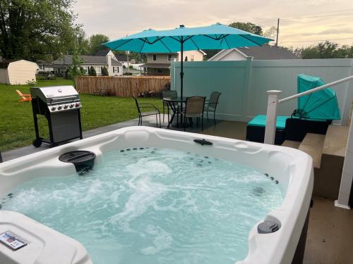 a hot tub in a backyard with a grill and an umbrella at Perfect Family Getaway! Steps from Attractions in Hummelstown