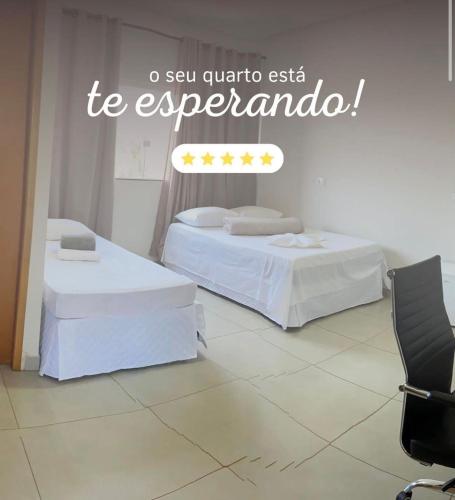 two beds in a room with a sign on the wall at Hotel Cerrado in Iraí de Minas