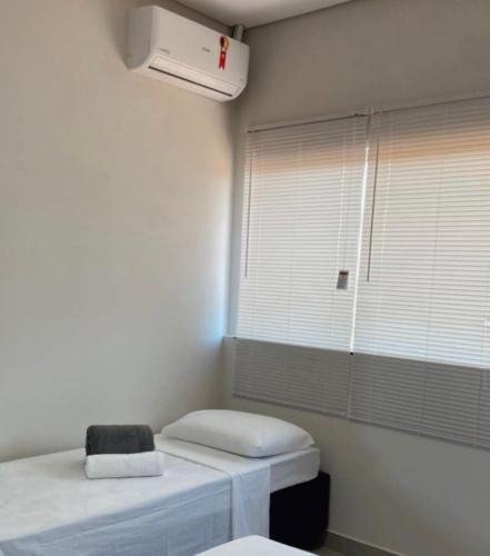 a room with two beds and a window with a heater at Hotel Cerrado in Iraí de Minas