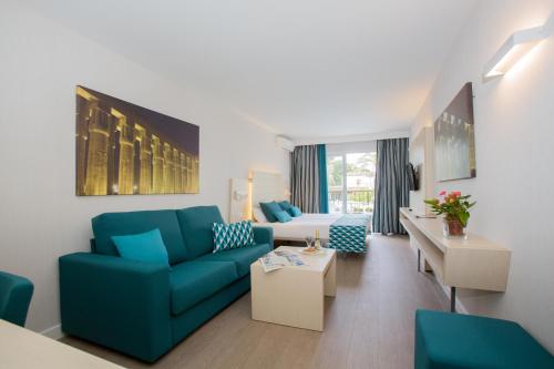 a living room with a blue couch and a bed at Hotel Luxor in Playa de Palma