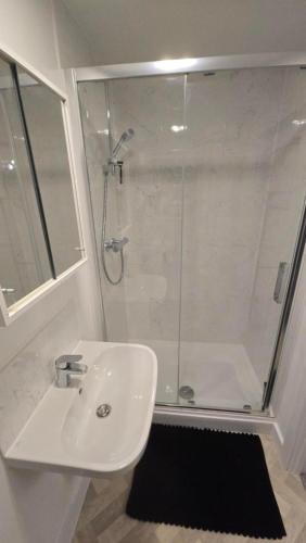 a white bathroom with a shower and a sink at 3,Lime Tree Ave in Haverfordwest