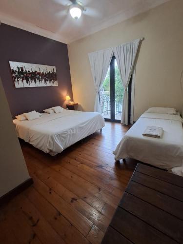 two beds in a room with wooden floors and windows at Le Vrero Boutique Hotel in Colonia del Sacramento