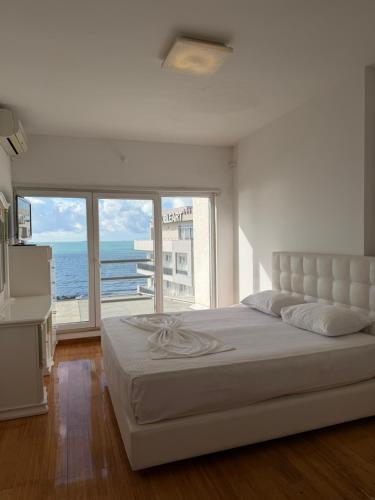 a bedroom with a large bed with a view of the ocean at Blumont aparthotel durres in Durrës