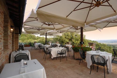 a restaurant with white tables and chairs and umbrellas at Locanda Della Picca in Città della Pieve