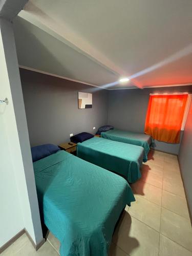 a room with three green beds and a window at Hostal JV Loft Triple in Nogales