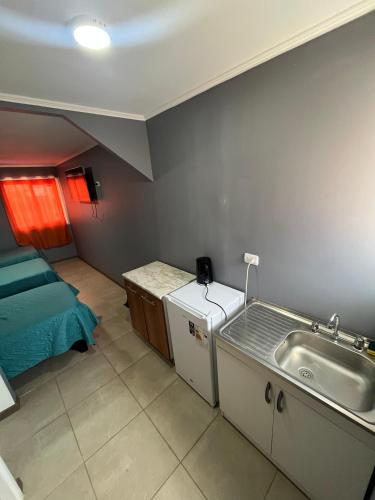 a small kitchen with a sink and a bed at Hostal JV Loft Triple in Nogales