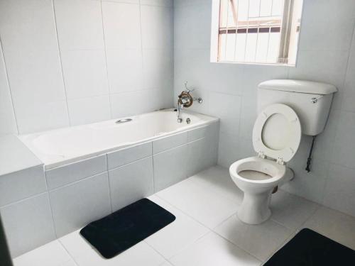 a white bathroom with a toilet and a bath tub at Sea Breeze Manor - Sage Unit in East London