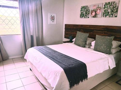 a bedroom with a large bed with white sheets at Sea Breeze Manor - Sage Unit in East London