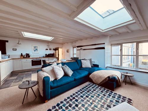 a living room with a blue couch and a kitchen at The Roundhouse Tregonce, Padstow, near the sea in St. Issey