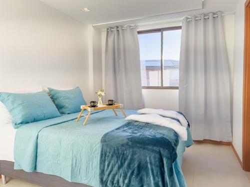 a bedroom with a bed with a table and a window at Duplex com Piscina Privativa em Itacimirim! in Camaçari