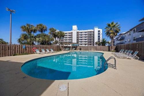 a swimming pool with chairs and a building in the background at Wind Drift North 214 2BD, 2BA in Orange Beach