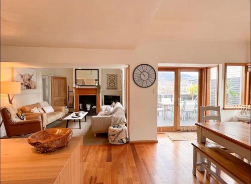 a living room with a couch and a clock on the wall at Best Location in Hobart! Luxury 4 bedroom with stunning views in Hobart