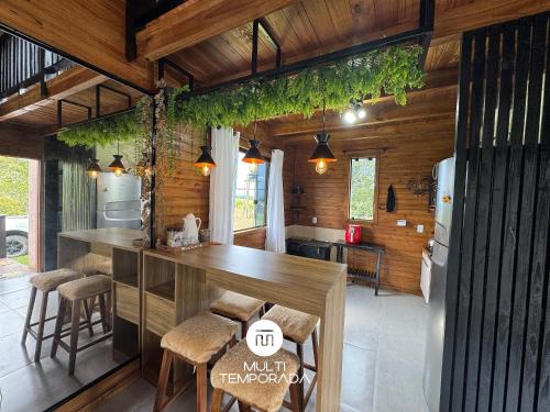 a kitchen with wooden walls and a counter with stools at Chalé do Campinho - Rancho Queimado/SC in Rancho Queimado