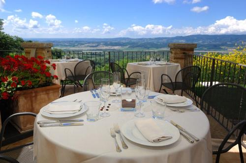 a table with white plates and silverware on a balcony at Locanda Della Picca in Città della Pieve