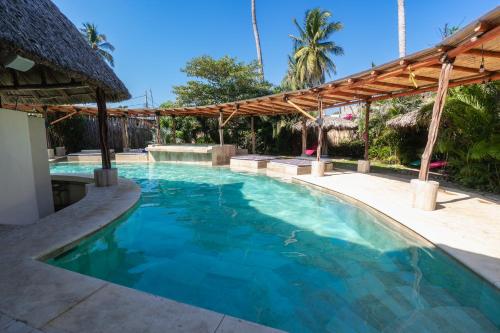 a swimming pool with a pergola and blue water at Ashly Loma Larga in Acapulco