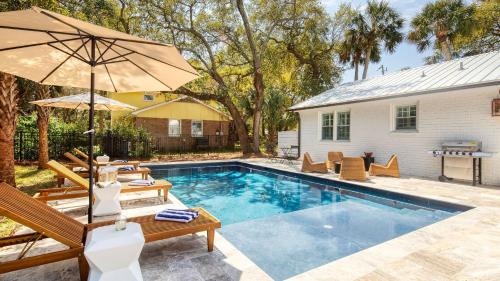 a pool with chairs and an umbrella next to a house at Sawyer by AvantStay Stunning Isle Of Palms Home w Pool in Isle of Palms